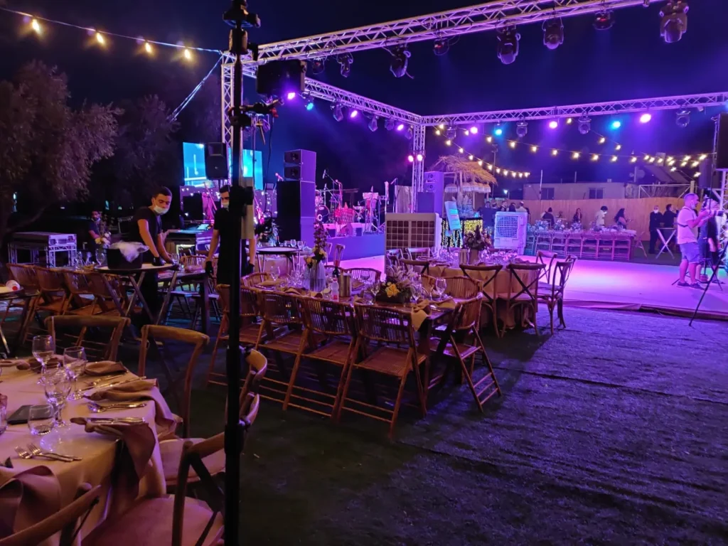 אירוע ערב בחוות הדקלים עם במה מוארת ושולחנות ערוכים במרחב פתוח